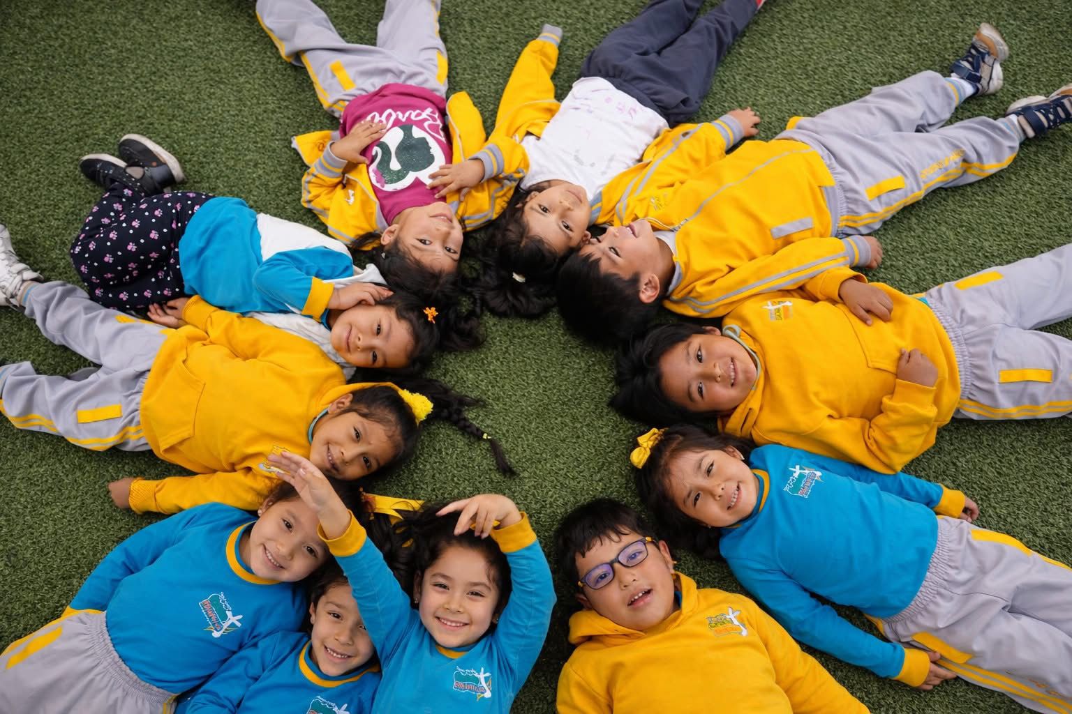 Niños felices en círculo con uniforme azul y amarillo en Cuna Jardín Cristo Blanco, Arequipa
